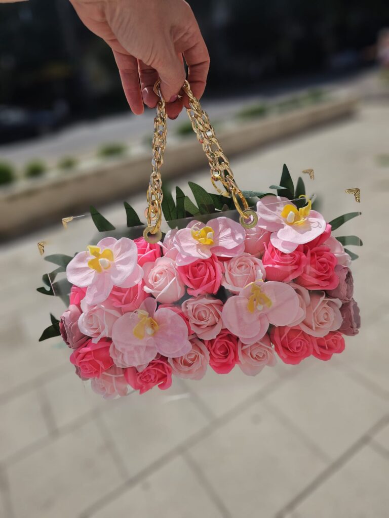 Meta Title SEO Geantă Acrilică cu Trandafiri, Orhidee și Camelia din Săpun | Cadou Premium | Royal Flowers Constanța Meta Description Descoperă geanta acrilică premium decorată cu trandafiri roz, orhidee și camelia din săpun parfumat. Un cadou elegant și de lungă durată, realizat manual de Royal Flowers Constanța. Ideal pentru aniversări, 8 Martie, Valentine's Day și alte ocazii speciale. H1 Geantă Acrilică Premium cu Trandafiri, Orhidee și Camelia din Săpun Un cadou exclusivist care îmbină eleganța florilor cu frumusețea unui accesoriu de lux Surprinde persoana dragă cu un cadou deosebit, creat pentru a impresiona și a rămâne o amintire prețioasă. Geanta Acrilică Premium cu Trandafiri, Orhidee și Camelia din Săpun este o creație florală exclusivă, realizată manual în atelierul Royal Flowers Constanța, unde fiecare detaliu este atent lucrat pentru a oferi un produs elegant și sofisticat. Realizată din acril transparent de înaltă calitate, geanta este decorată cu trandafiri roz, flori de orhidee și o camelia, toate confecționate din săpun parfumat premium. Aspectul lor delicat reproduce fidel frumusețea florilor naturale, iar parfumul discret completează experiența acestui cadou special. Designul este pus în valoare de mânerele metalice aurii și de aranjamentul floral bogat, transformând geanta într-o piesă decorativă luxoasă, potrivită atât pentru a fi oferită în dar, cât și pentru a decora elegant orice încăpere. Compoziție Trandafiri roz din săpun parfumat Flori de orhidee din săpun parfumat Floare de camelia din săpun parfumat Frunziș decorativ premium Geantă din acril transparent Mânere metalice aurii Design realizat integral manual Compoziția poate varia ușor în funcție de disponibilitatea materialelor, păstrând întotdeauna stilul, cromatica și valoarea produsului. Semnificația florilor 🌸 Trandafirii roz simbolizează iubirea, tandrețea, admirația și recunoștința. 🌺 Orhideea este simbolul eleganței, feminității, frumuseții rafinate și al luxului. Ea exprimă apreciere, respect și sentimente sincere. 🤍 Camelia reprezintă perfecțiunea, rafinamentul și dragostea profundă, fiind una dintre cele mai elegante flori utilizate în aranjamente premium. Împreună, aceste flori creează un cadou sofisticat, plin de simbolism și emoție. Avantajele florilor din săpun Florile din săpun sunt o alternativă elegantă la florile naturale, păstrându-și frumusețea pentru foarte mult timp. Beneficii Nu se ofilesc. Nu necesită apă sau întreținere. Își păstrează forma și culoarea ani la rând. Au un parfum discret și plăcut. Pot fi folosite ulterior ca obiect decorativ. Reprezintă un cadou elegant și original. Caracteristici Geantă acrilică transparentă premium Flori realizate integral din săpun parfumat Design exclusivist Produs handmade Mânere metalice aurii Aspect luxos și elegant Cadou decorativ de lungă durată Ambalare premium inclusă Ideală pentru ❤️ Ziua Îndrăgostiților ❤️ Dragobete ❤️ 8 Martie ❤️ Ziua Mamei ❤️ Zi de naștere ❤️ Onomastică ❤️ Aniversare ❤️ Cerere în căsătorie ❤️ Cadou pentru iubită ❤️ Cadou pentru soție ❤️ Cadou pentru mamă ❤️ Cadou pentru fiică ❤️ Cadou corporate Îngrijire Pentru a menține frumusețea aranjamentului floral: evitați contactul direct cu apa; păstrați produsul într-un loc uscat și răcoros; evitați expunerea îndelungată la lumina directă a soarelui; curățați geanta din acril cu o lavetă moale și uscată; manipulați florile cu grijă pentru a le păstra aspectul impecabil. Royal Flowers Constanța La Royal Flowers Constanța, realizăm cadouri florale premium și aranjamente unice, create pentru a transforma orice ocazie într-un moment memorabil. În atelierul nostru găsești buchete elegante, geanți florale din acril, aranjamente cu flori din săpun, flori criogenate, decoruri pentru evenimente și cadouri personalizate, toate realizate cu pasiune și atenție la detalii. Livrare rapidă în Constanța Poți comanda această geantă acrilică cu trandafiri, orhidee și camelia din săpun direct de pe www.royalflowers.ro sau din florăria noastră din Constanța. Asigurăm livrare rapidă în Constanța și împrejurimi, iar fiecare produs este ambalat cu grijă pentru a ajunge în condiții perfecte. URL recomandat https://www.royalflowers.ro/geanta-acrilica-trandafiri-orhidee-camelia-din-sapun SEO Title alternativ Geantă Acrilică cu Trandafiri, Orhidee și Camelia din Săpun | Royal Flowers Constanța Alt Text Imagine Geantă acrilică transparentă cu trandafiri roz, orhidee și camelia din săpun parfumat, realizată manual de Royal Flowers Constanța, cadou premium pentru ocazii speciale. Cuvinte cheie SEO geantă acrilică cu flori din săpun, geantă cu trandafiri din săpun, geantă cu orhidee din săpun, geantă cu camelia din săpun, flori din săpun Constanța, aranjament cu flori din săpun, geantă florală premium, cadou elegant Constanța, cadou pentru femei, cadou aniversare, cadou Valentine's Day, cadou 8 Martie, florărie Constanța, Royal Flowers Constanța, cadouri premium, cadouri personalizate, livrare flori Constanța, geantă transparentă cu flori.